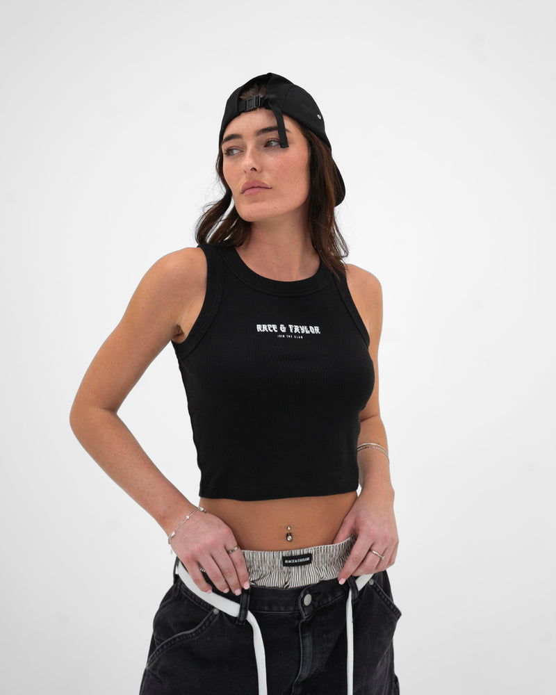 A female model wearing a black ribbed, cropped racer vest with the text 'R&R' printed on the front.