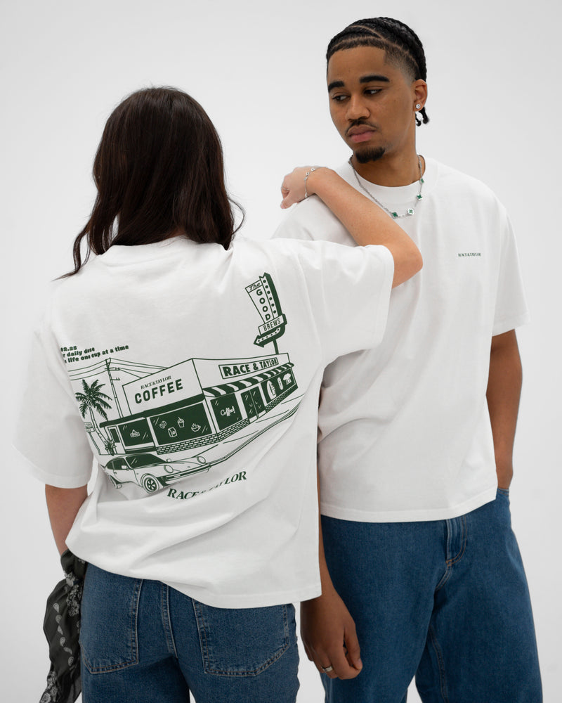 Two models wearing white heavy t-shirts with a graphic print on the back, standing in a casual setting.