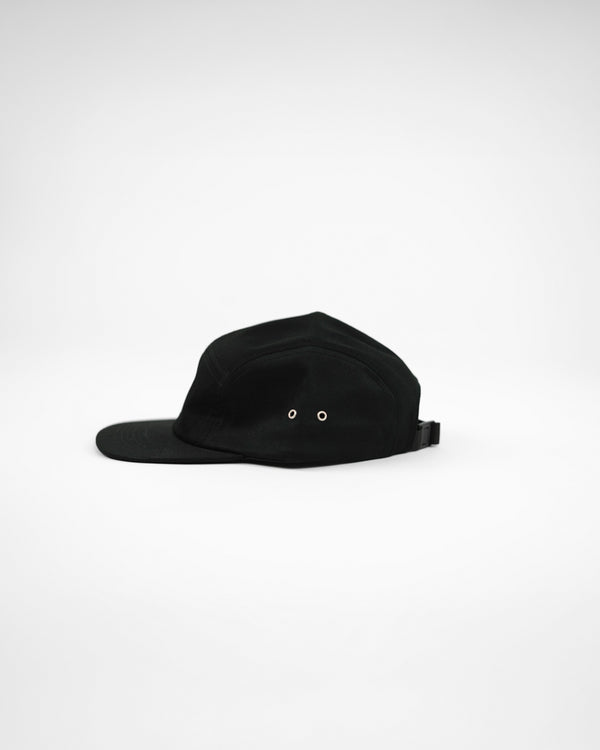 A black five-panel skater cap with an adjustable fastener, flat peak, and no visible brand markings.

